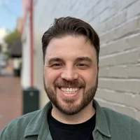 Portrait of Zack Baker, Roamler's Head of Sales, smiling outside a brick building